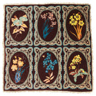 Flat-lay of brown velvet bedcover showing six oval botanical floral medallions in teal, yellow, and pink with cream fringe trim