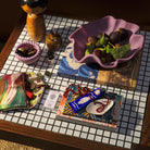 Lifestyle scene with orchid ceramic bowl holding fresh figs on mosaic table with decorative items