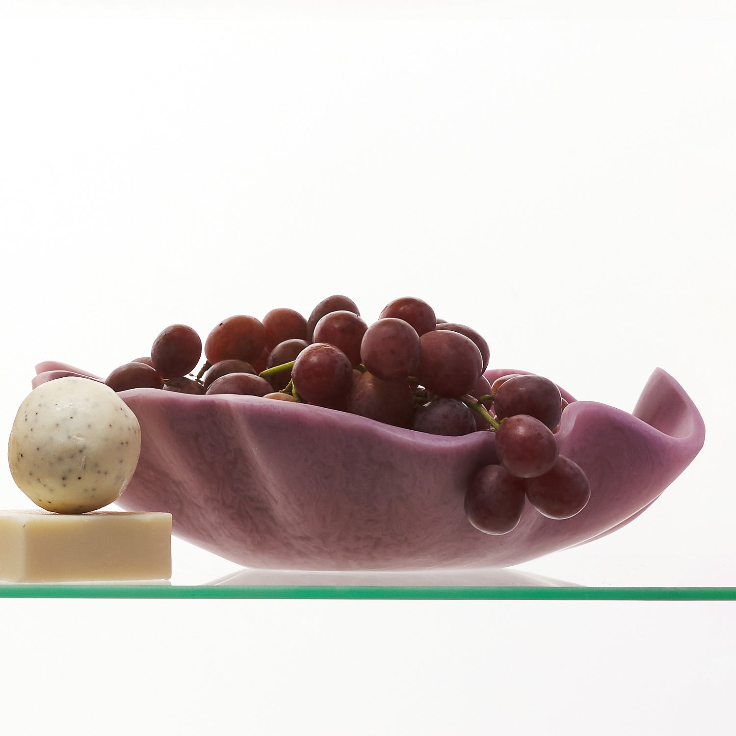 Color family display with yellow ceramic bowls and orchid bowl holding grapes on glass shelves