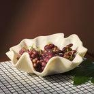 Close-up of pearl ceramic bowl holding fresh red grapes on black wire rack surface
