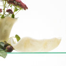 Pearl ceramic bowl arranged with flowers and colorful bowls on glass shelving display