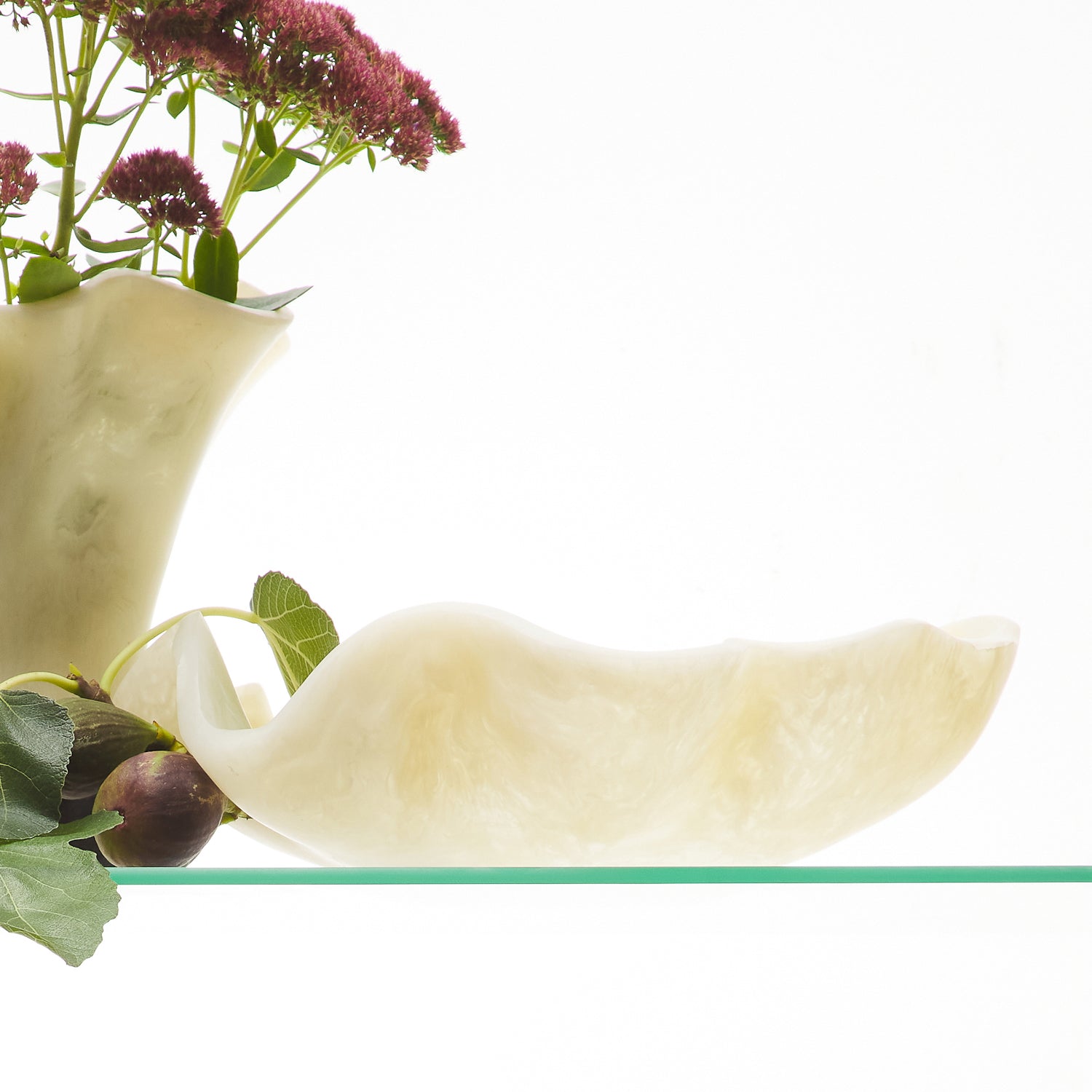 Pearl ceramic bowl arranged with flowers and colorful bowls on glass shelving display