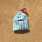 Striped bag with red drawstring on a beige textured background