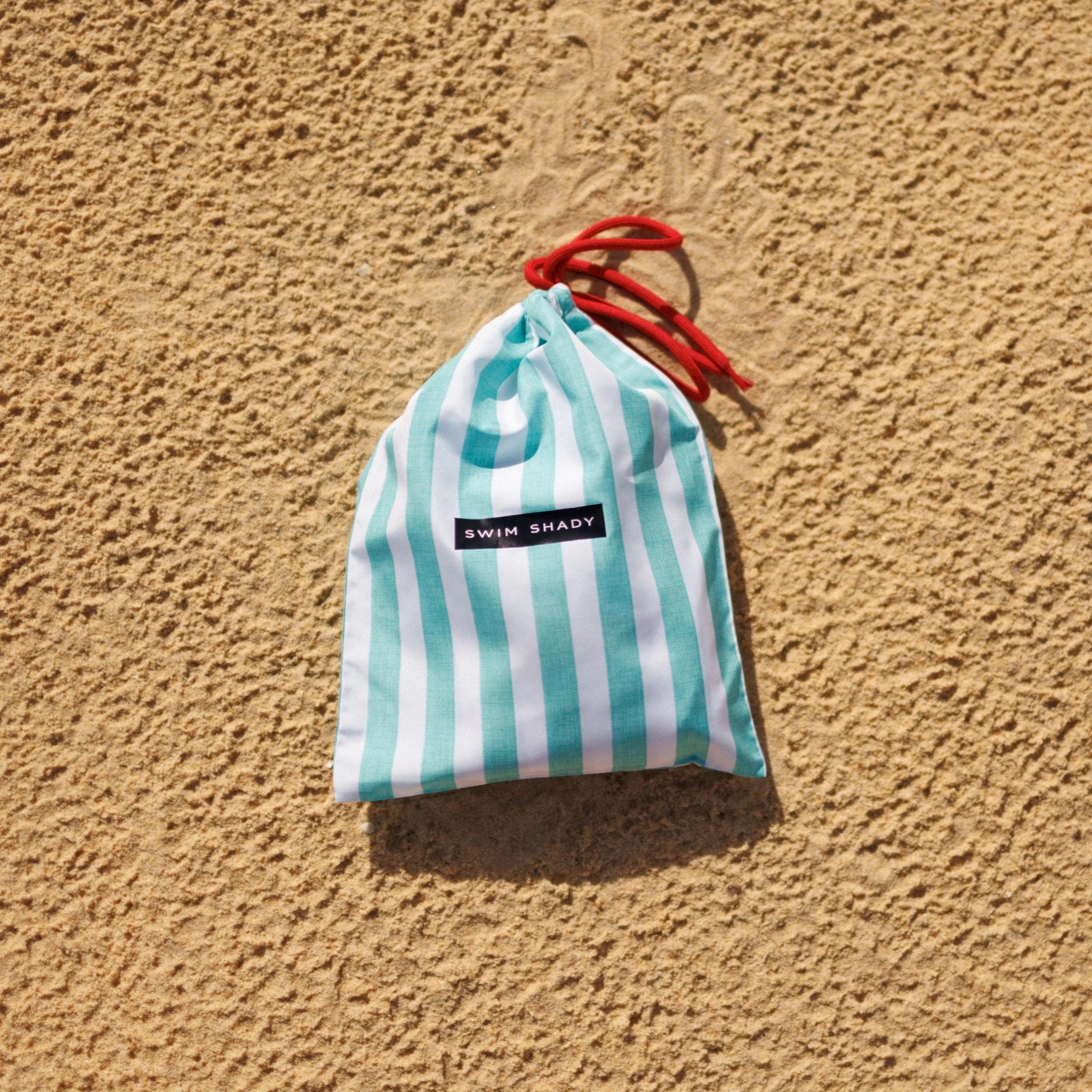 Striped bag with red drawstring on a beige textured background
