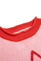 Close-up of red ribbed crew neckline detail on pink Neve Knit sweater
