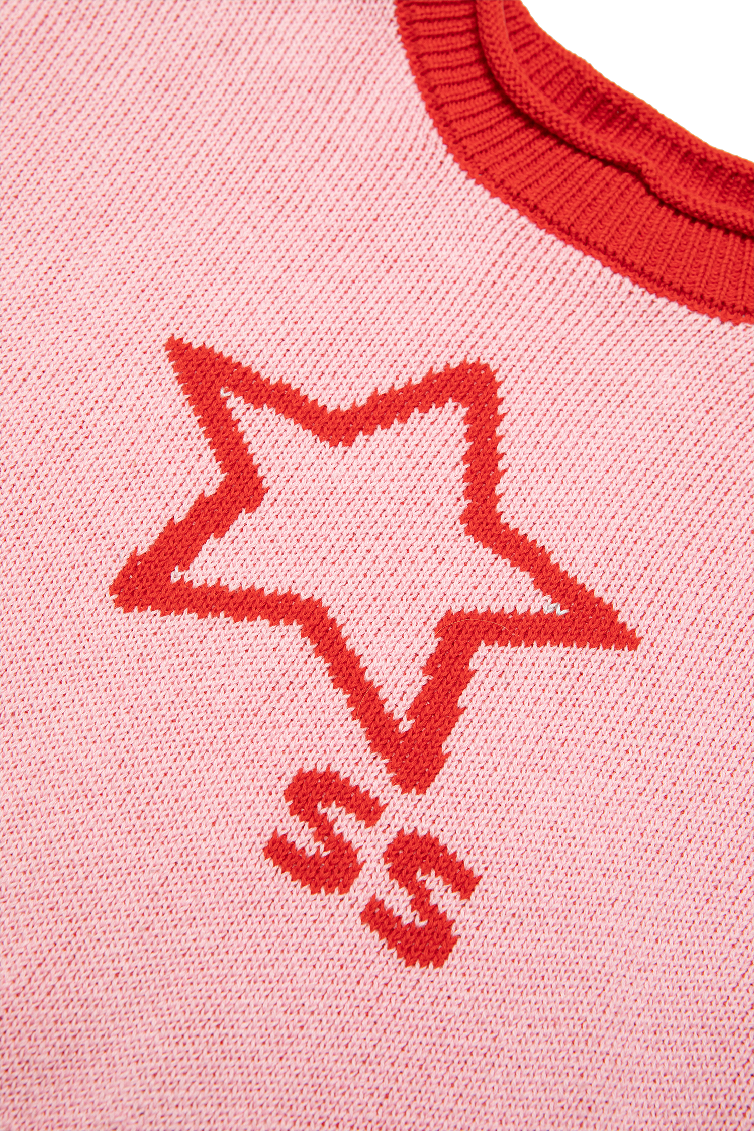 Close-up detail of red star outline and SS lettering on pink knit sweater fabric