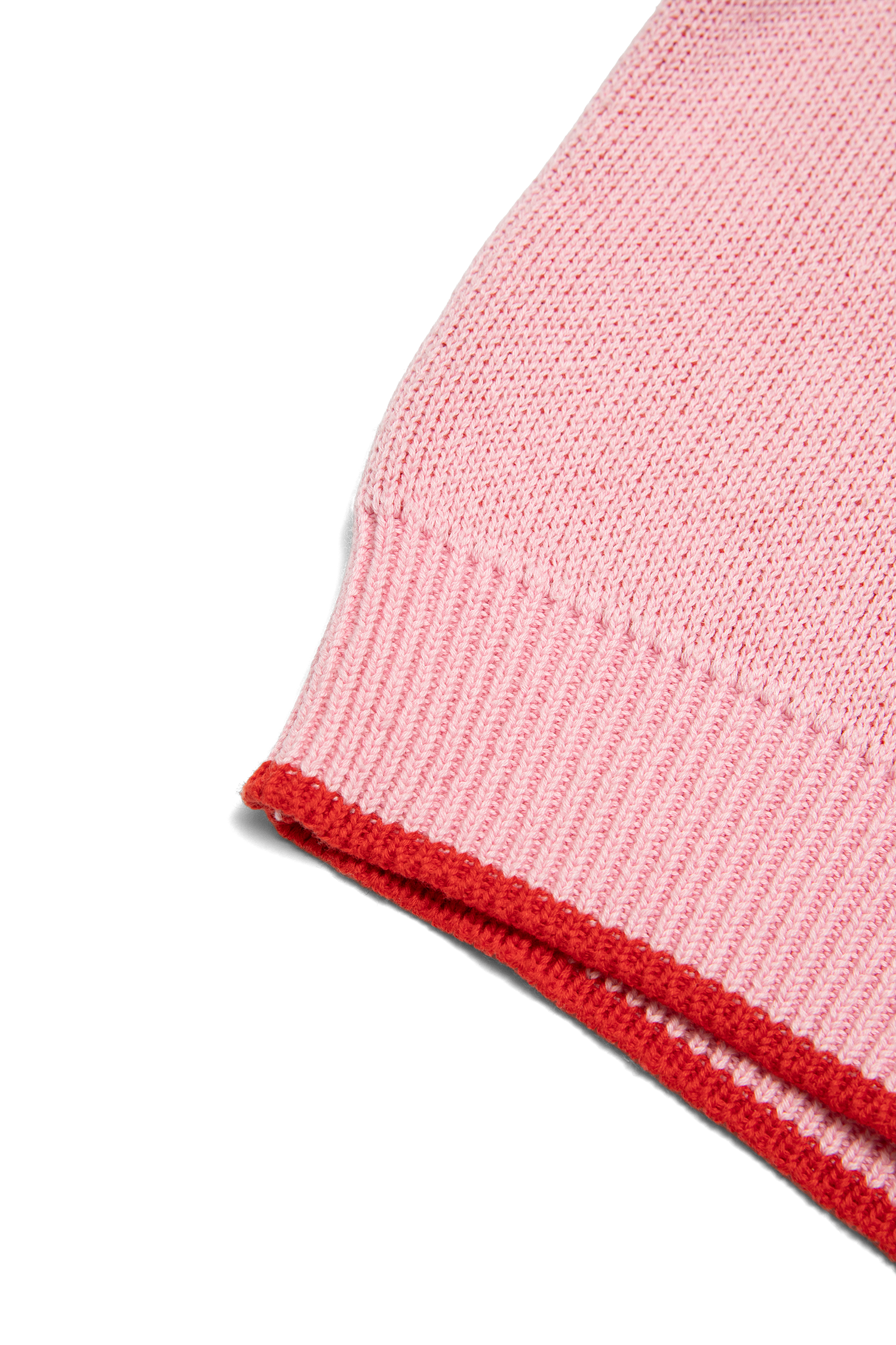 Detail shot of pink knit sweater sleeve hem showing red contrast ribbed cuff trim