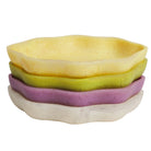 Stack of four colorful ceramic serving dishes in yellow, green, pink and cream tones