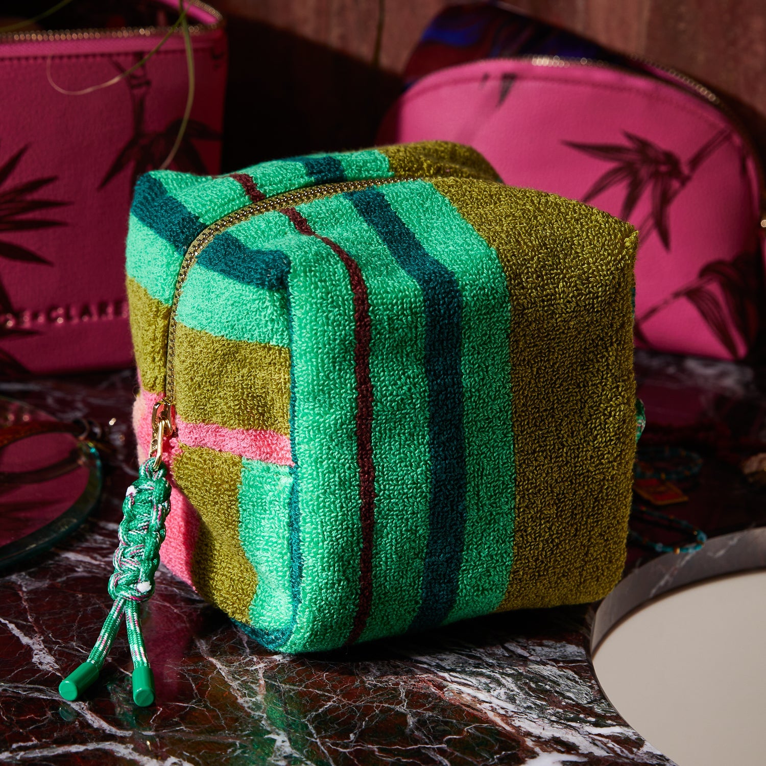 Side view of Nicolette Terry Pouch Juniper displaying colorful striped terry cloth fabric and rope zipper pull