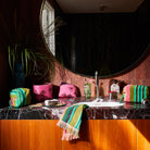 Bathroom vanity styling with multiple Nicolette Terry Pouches and matching striped towel in modern marble setting