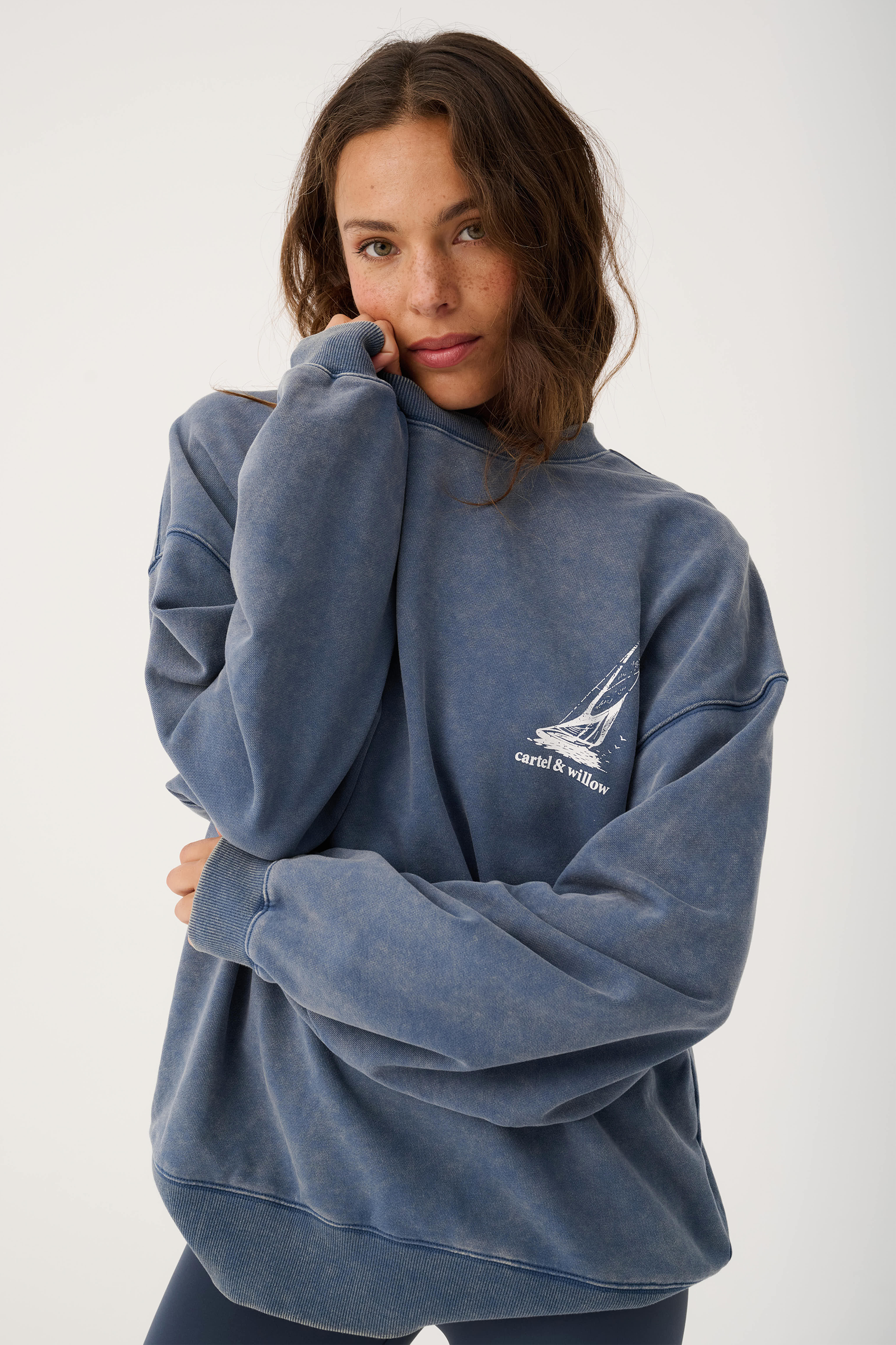 Front view of Nina Sweater in blue showing oversized fit with small sailboat logo on chest