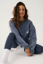Seated front view of Nina Sweater showing crew neck and small sailboat emblem detail