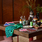 Paige pot holder set styled with kitchen accessories and polka dot tea towel in dining setting