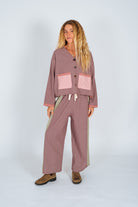 Side view of woman in Atmosea Patchwork Pant Houndstooth Combo holding surfboard at beach