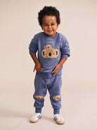 Child wearing blue Huxbaby Peekaboo Kel Pocket Sweatshirt with koala applique design in full body front view