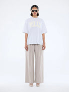 Model wearing Pelly Collegiate Tee White Marle by Ena Pelly - white tshirt with cream yellow text "Pelly"