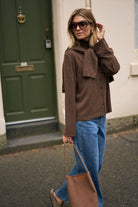 Side profile of woman wearing chocolate marle knit cardigan with high neck and oversized sleeves
