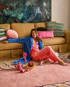 Woman relaxing on sofa wearing blue Pie In The Sky Adult Cosy Robe with colorful cushions