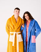 Couple wearing matching Kip & Co adult cosy robes in blue and yellow waffle textured fabric