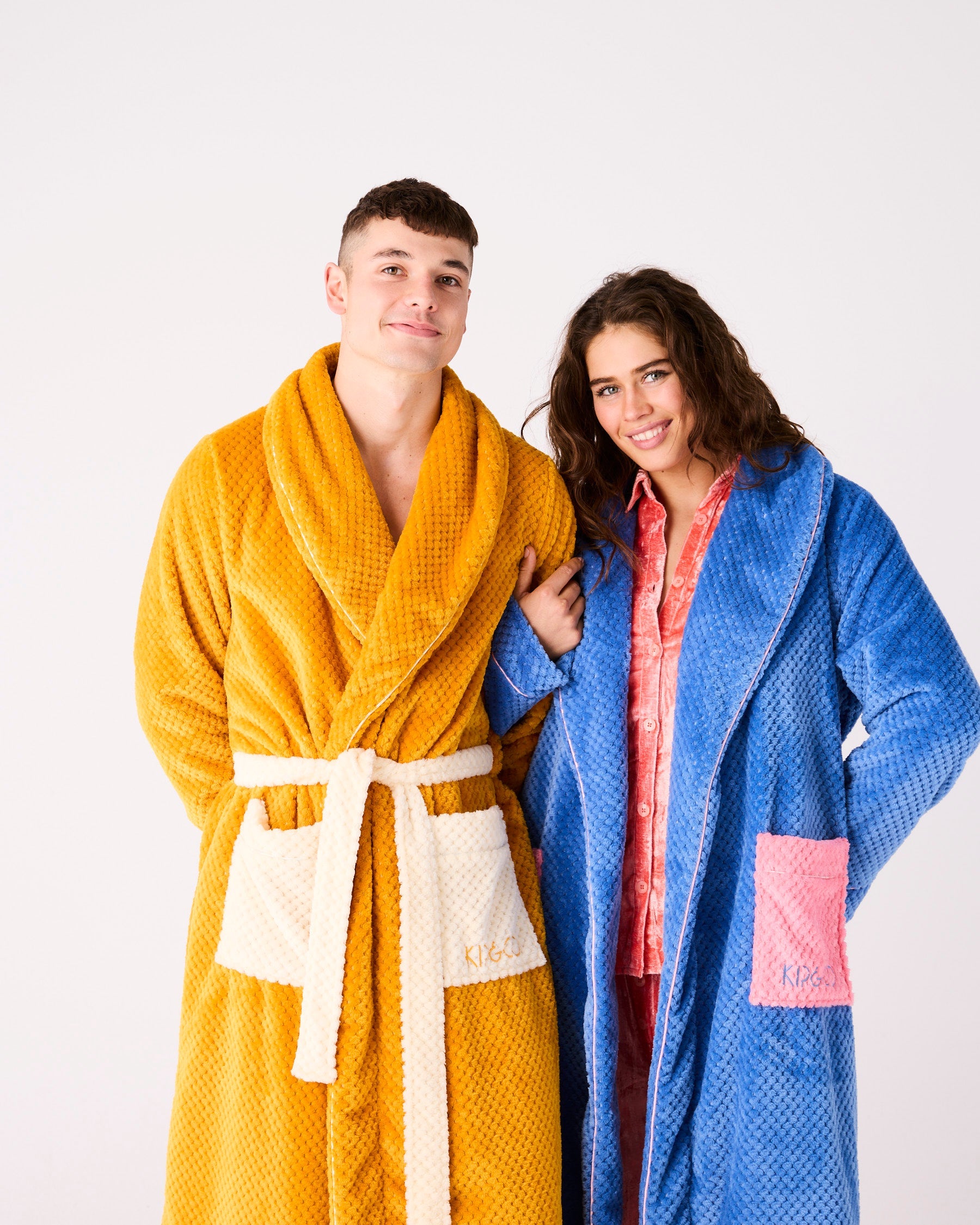 Couple wearing matching Kip & Co adult cosy robes in blue and yellow waffle textured fabric