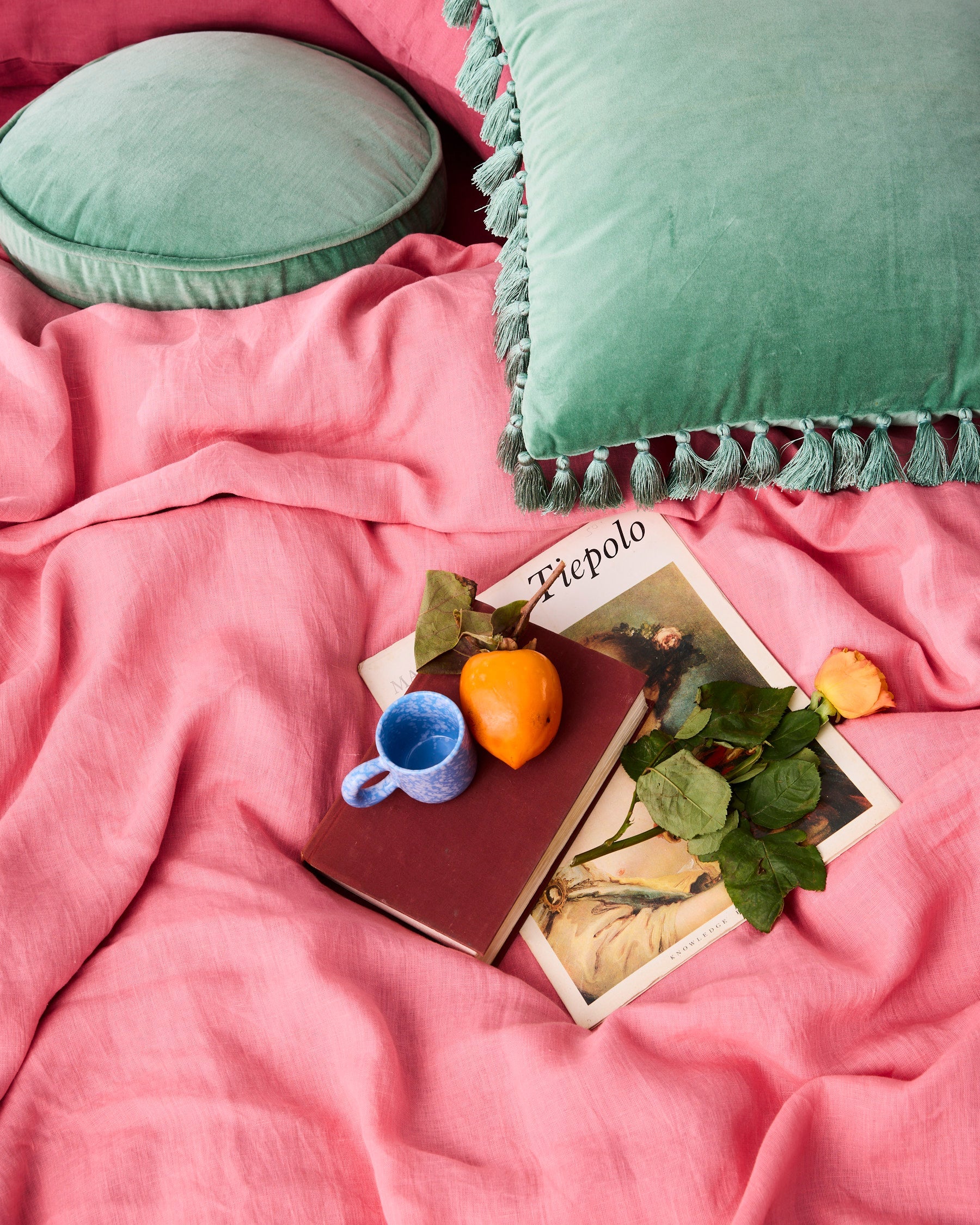 Pistachio velvet tassel cushion styled with pink bedding and colorful lifestyle props