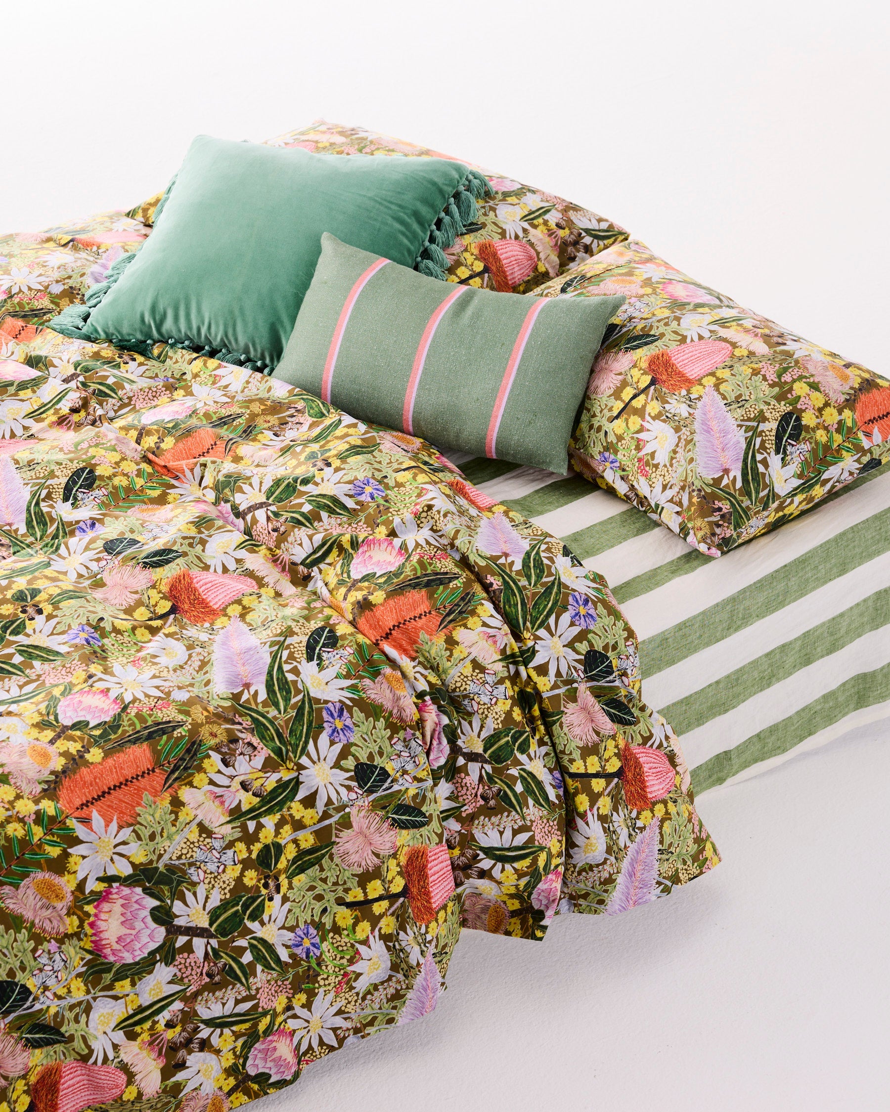 Pistachio velvet tassel cushion arranged on floral bedding with coordinating green pillows