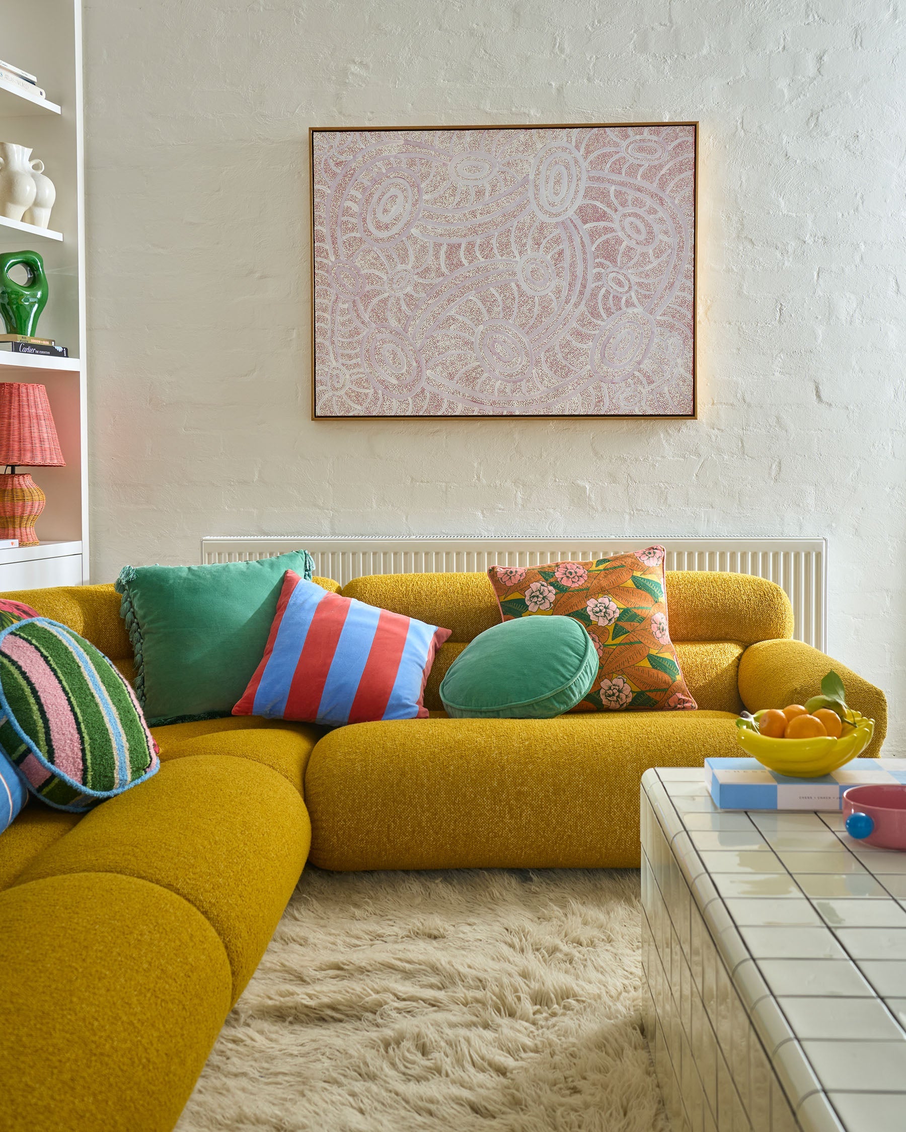 Pistachio velvet tassel cushion styled on yellow sectional sofa in modern living room