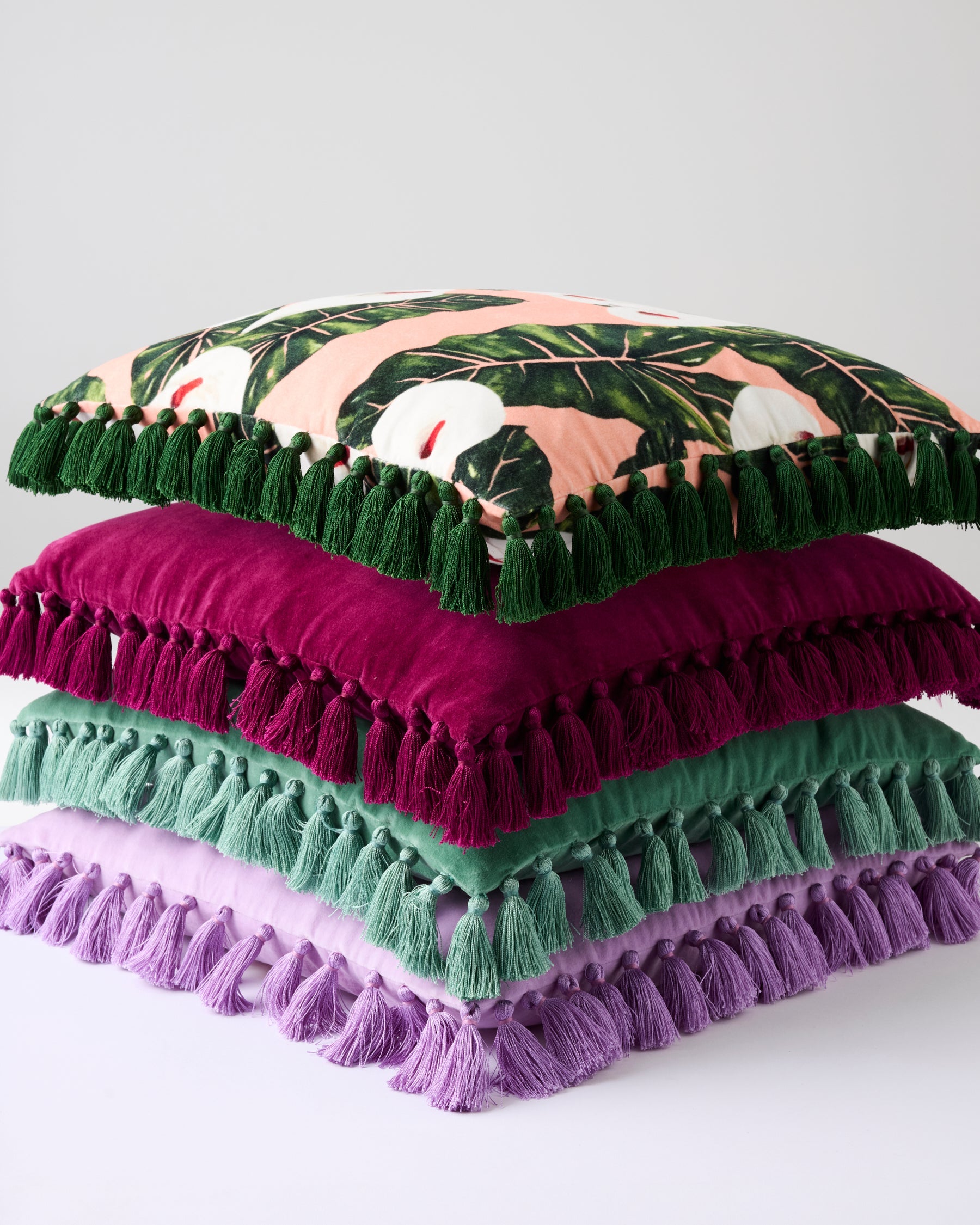 Stack of colorful velvet tassel cushions showing pistachio magenta green and lavender options