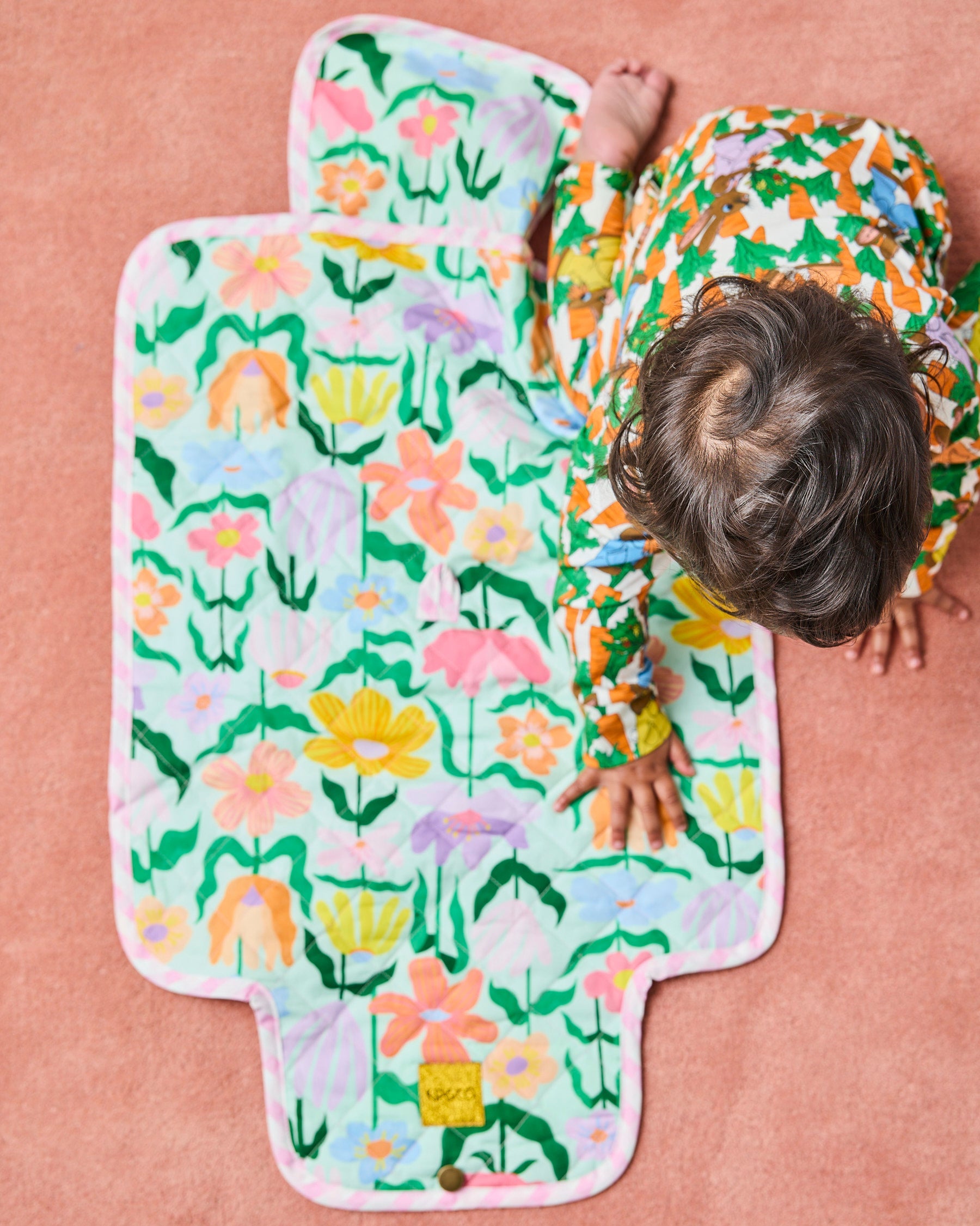 Overhead view of Popping Flowers Green Baby Change Mat by Kip Co displaying vibrant flower design and contoured shape