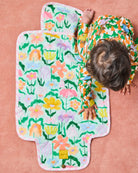 Overhead view of Popping Flowers Green Baby Change Mat by Kip Co displaying vibrant flower design and contoured shape
