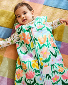 Baby wearing Kip & Co Popping Flowers Green Sleep Bag 2.5 Tog on colorful geometric rug