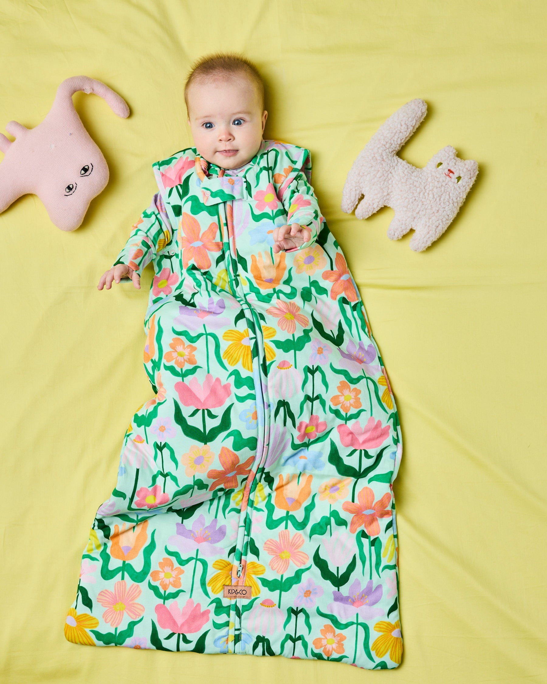 Full view of Popping Flowers Green Sleep Bag 2.5 Tog with baby and toys on yellow background