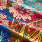 Close-up detail of vibrant red, blue, pink and yellow floral print on glossy silk fabric