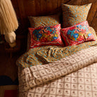 Two red floral silk pillowcases with oval bouquet print on a rustic wood-panelled bedroom bed