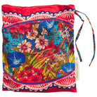 Red floral silk pillowcase shown in its matching drawstring storage bag with branded label