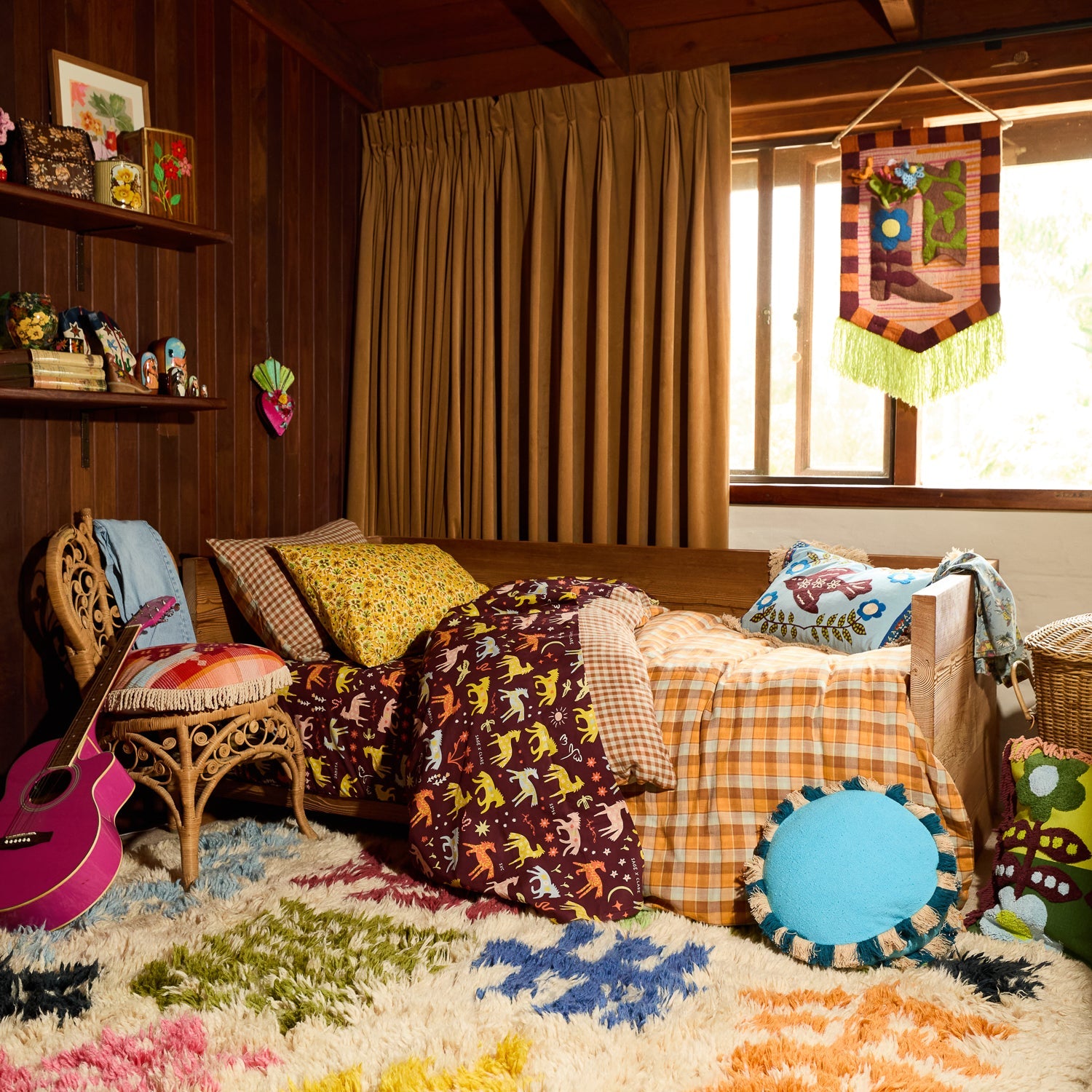 Turquoise round fringe cushion styled on the floor of a boho bedroom beside a patterned bed