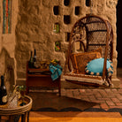 Turquoise round cushion with teal and natural fringe edge styled in a hanging rattan egg chair