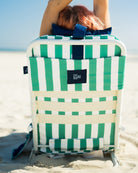 Woman relaxing on Riviera Beach Lounger by the ocean with drink in cup holder