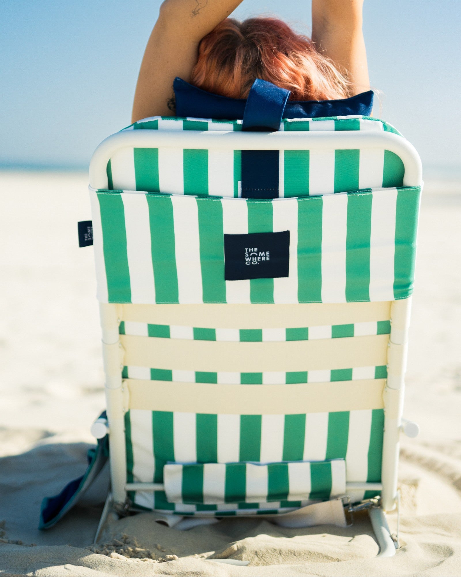Woman relaxing on Riviera Beach Lounger by the ocean with drink in cup holder