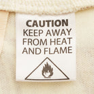 Close-up of care label on Rosalia Kids Poncho showing safety warning for heat and flame