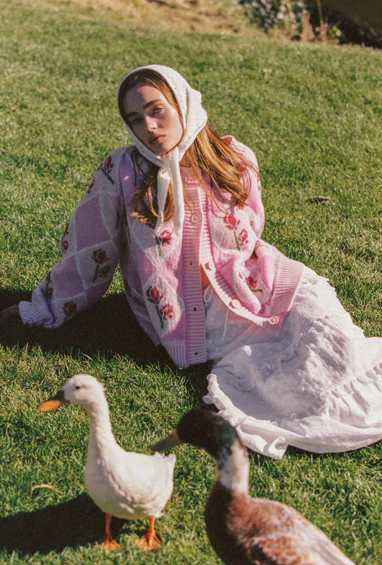 female model sitting down wearing the Rosie Cardigan by JUNI with ducks around her
