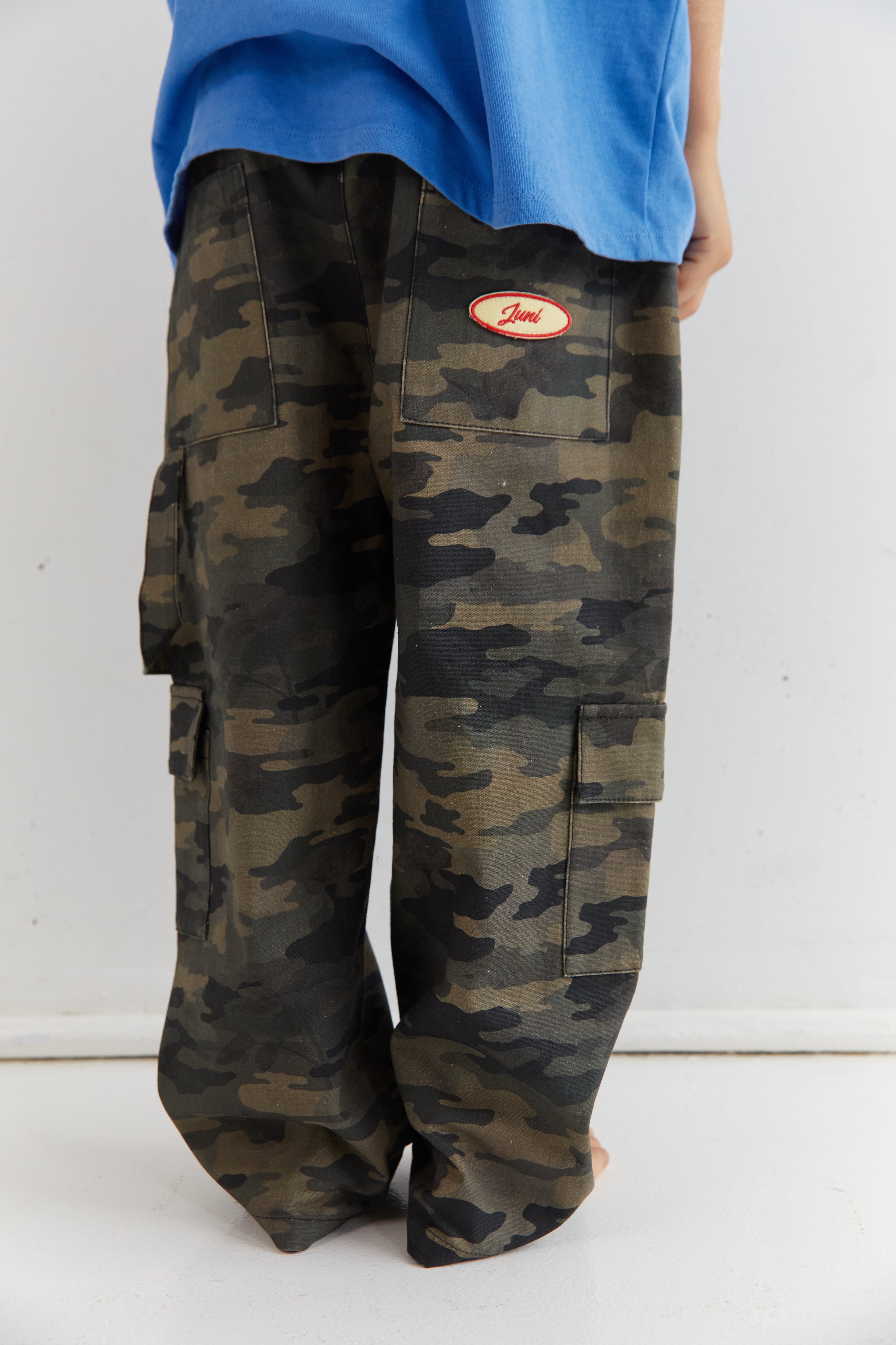 Close-up of Scottie Pants camo cargo pockets with Juni brand label detail