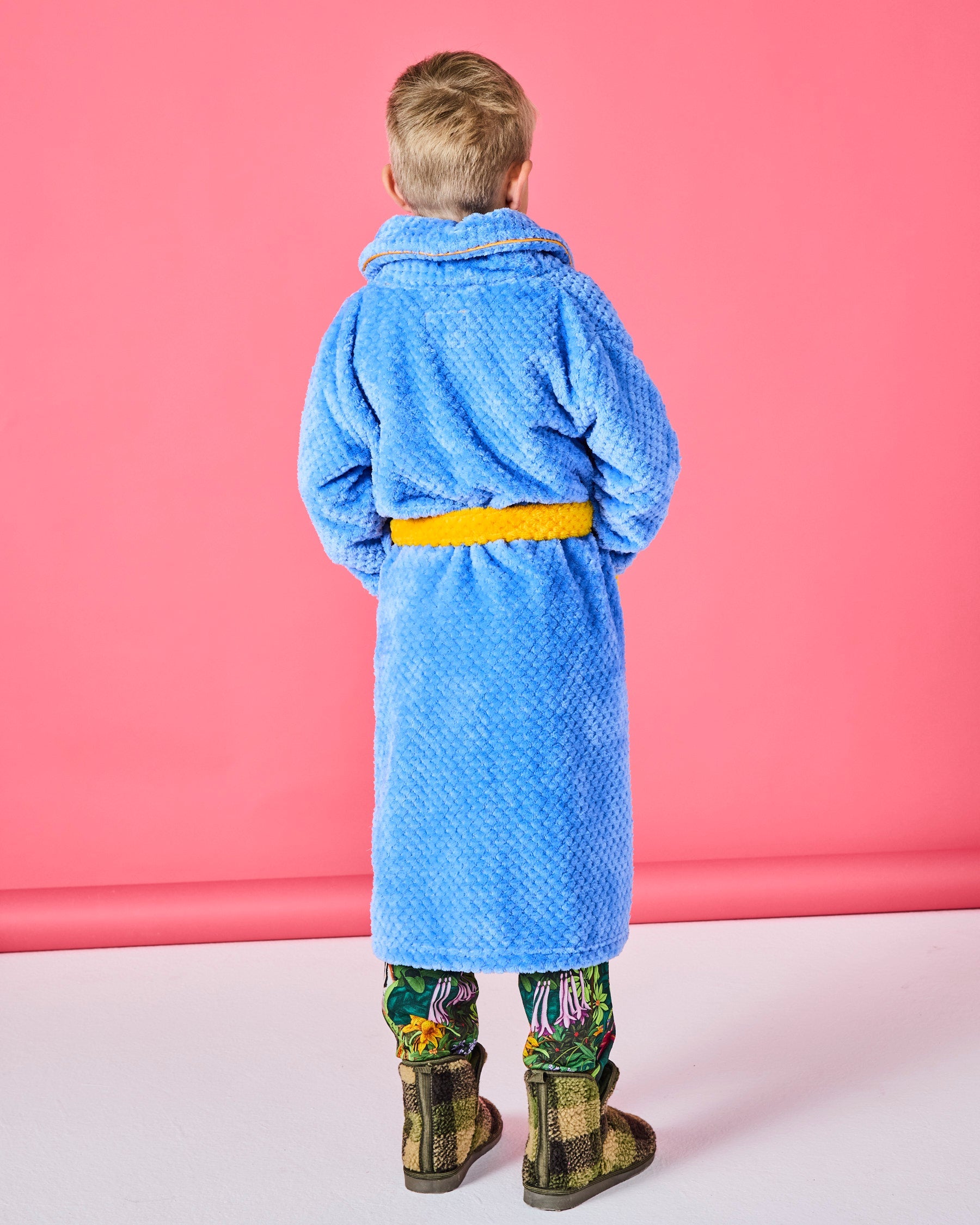 Wide outdoor view of family wearing Seaside Kids Cosy Robes by Kip & Co walking in golden field