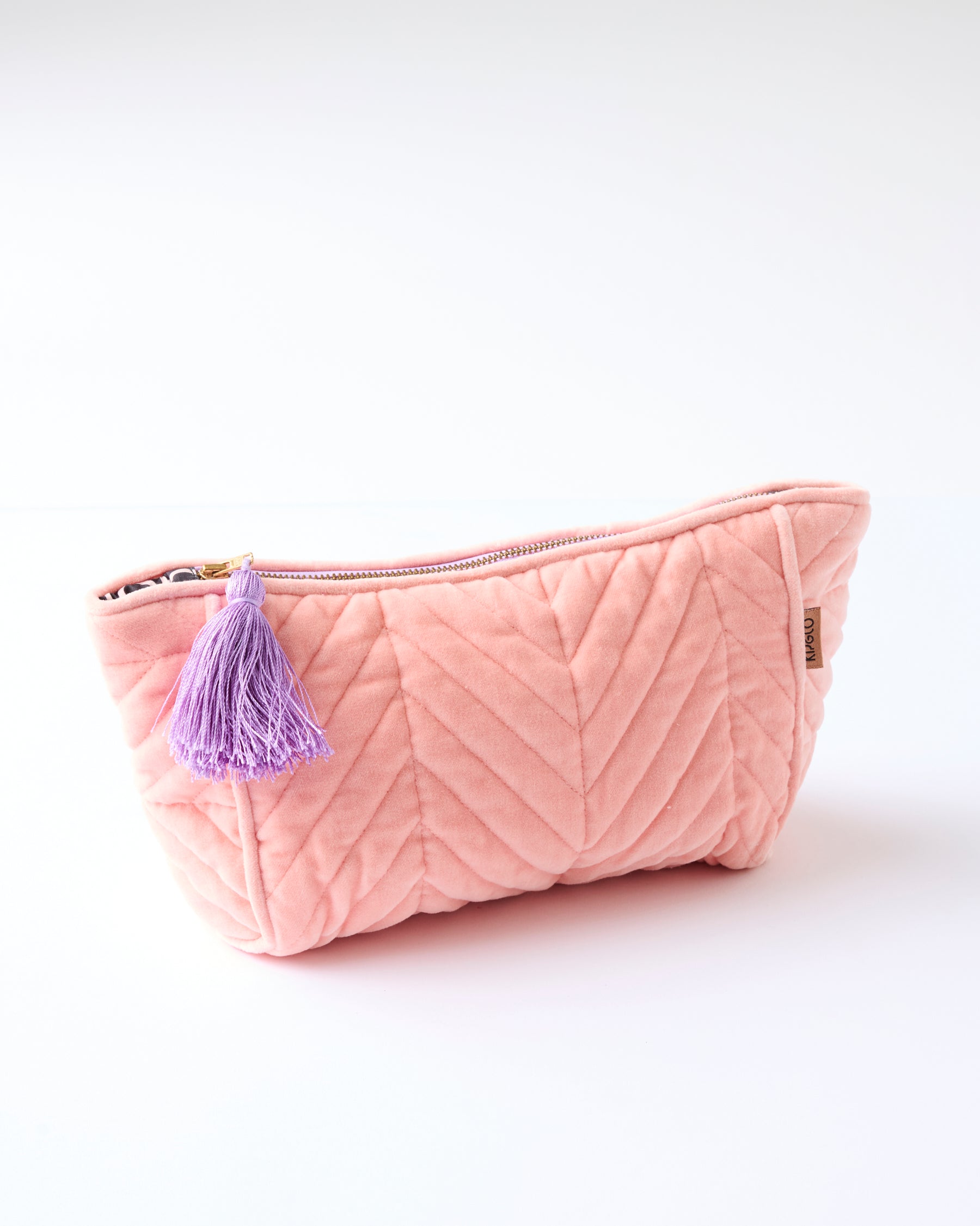Kip & Co Sherbet Velvet Toiletry Bag in coral pink with quilted chevron pattern and purple tassel charm