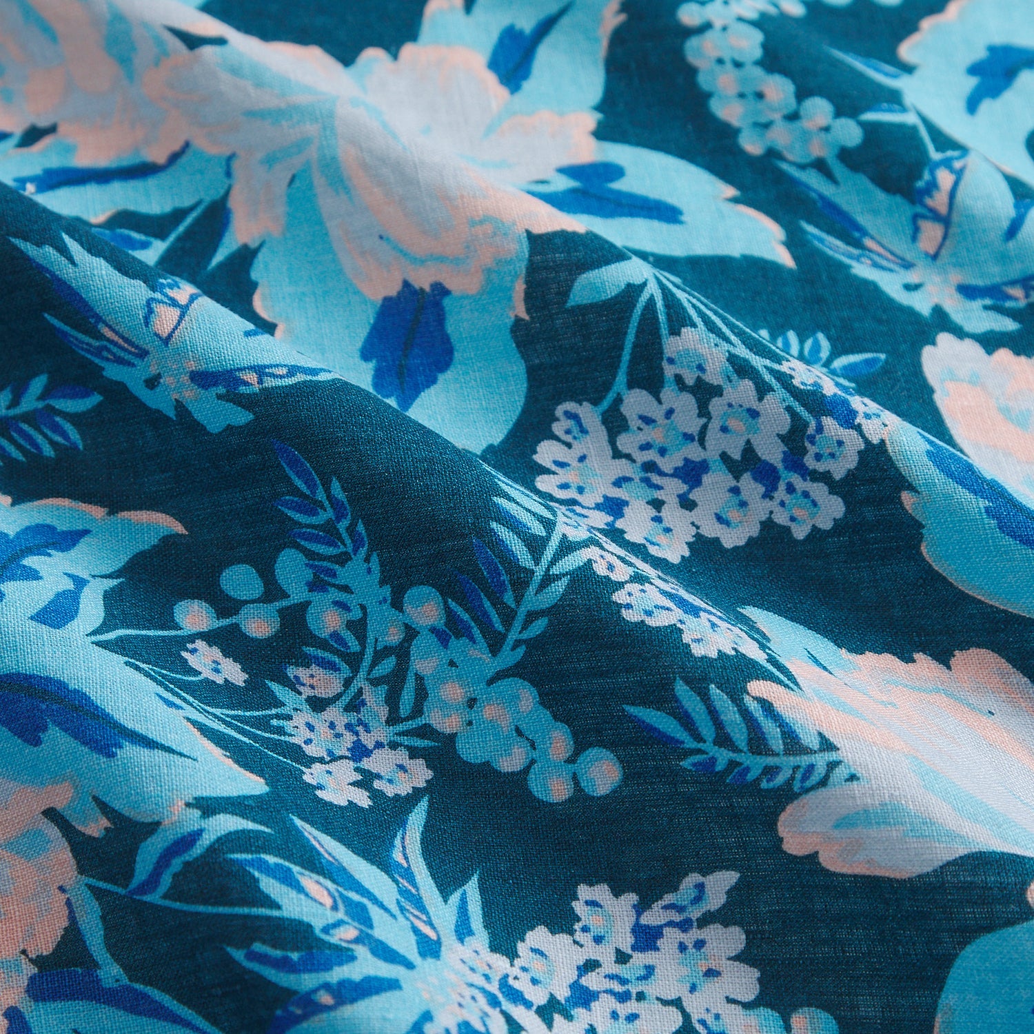 Macro detail of teal linen fabric with blue and blush pink floral botanical print showing texture