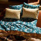 Teal and blush floral linen sheet and pillowcase set styled on a bed in warm sunlight