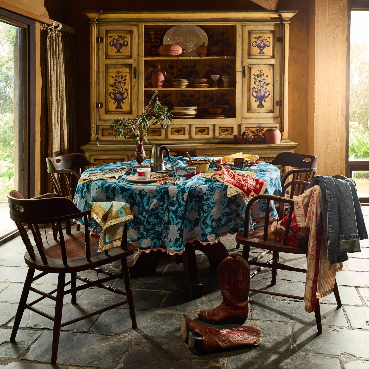 Teal blue floral tablecloth draped over a round dining table in a rustic room
