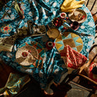 Overhead view of teal floral tablecloth on a set dining table with plates and food