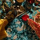 Close-up overhead shot of dark teal and blush floral tablecloth on a styled table