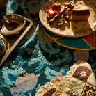 Detail of teal floral tablecloth with peach scalloped edge on a styled dining table
